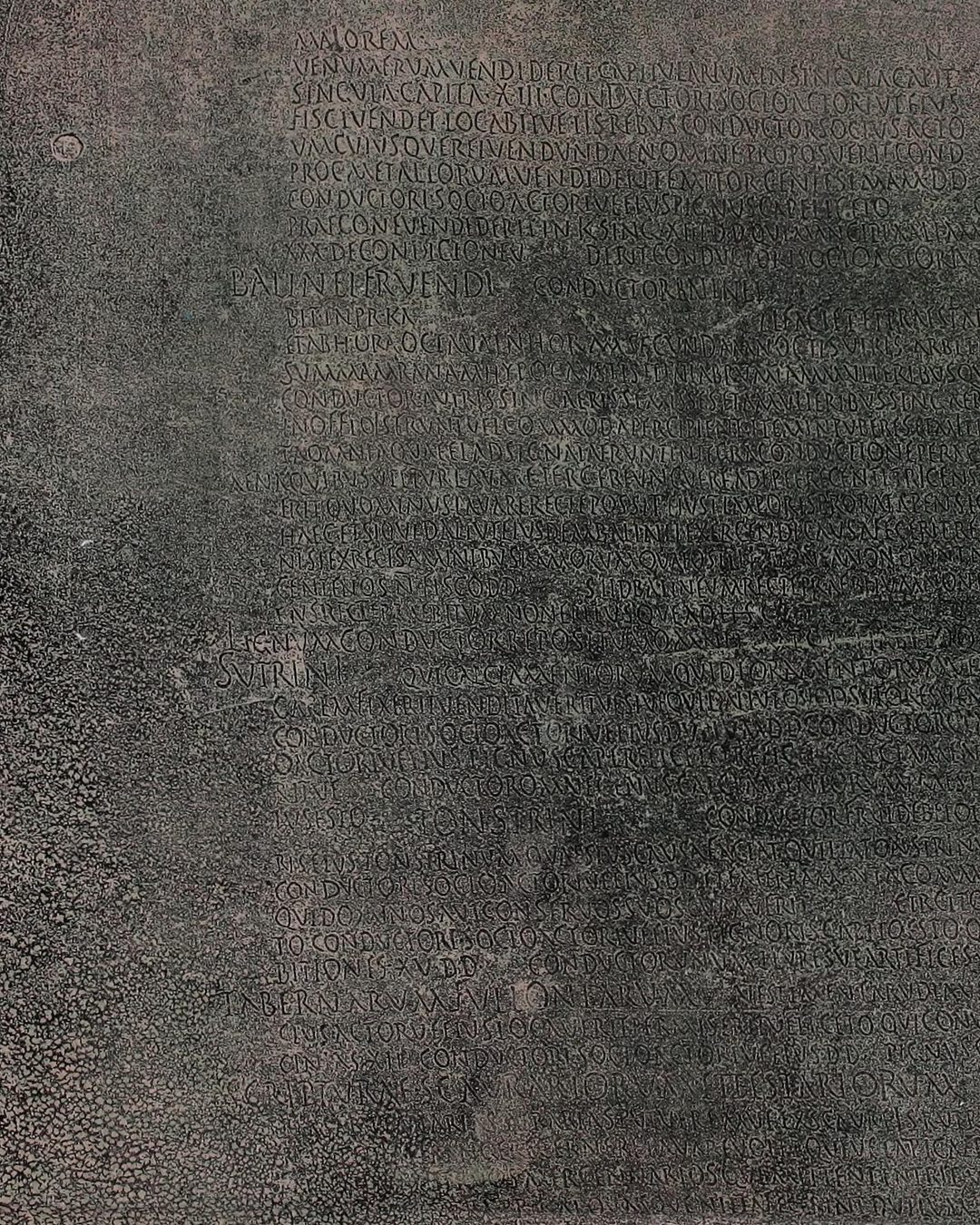 Pormenor da estampa 1 da mesma memória de Estácio da Veiga (1880): no bronze leem-se os títulos dos capítulos, BALINEI FRVENDI, os banhos; SVTRINI, os sapateiros; TONSTRINI, os barbeiros (Internet Archive, exemplar do Getty Research Institute, domínio público).