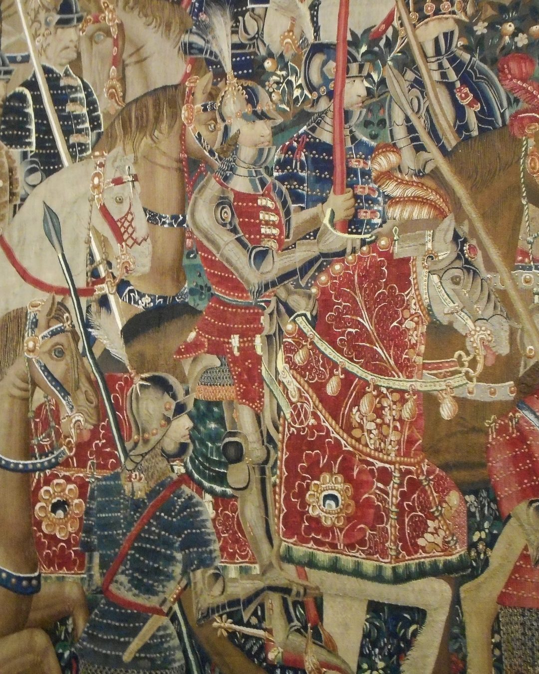 Pormenor da tapeçaria da Entrada em Tânger, tecida na Flandres nos anos que se seguiram a 1471: à frente da marcha, de armadura e brocado vermelho, o cavaleiro identificado como D. João, filho do duque de Bragança, que Afonso V mandou tomar posse da cidade (Museu Paroquial de Tapeçarias de Pastrana; Wikimedia Commons, domínio público).